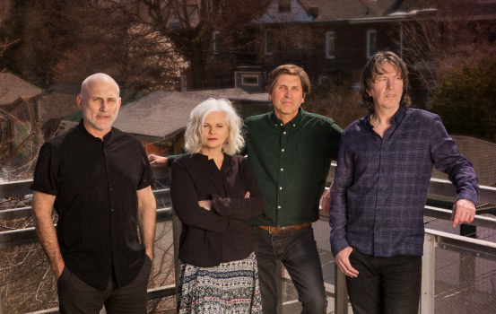 Cowboy Junkies posed on balcony with house in background.