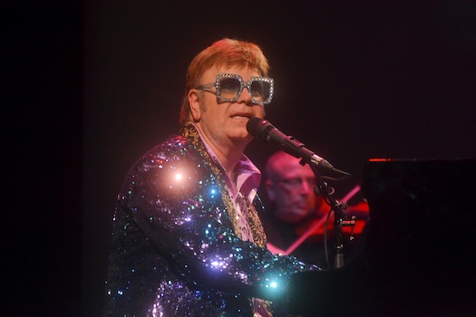 Elton Rohn in sparkly Jacket on stage singing into microphone